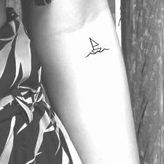 a woman's arm with a small sailboat tattoo on the left side of her arm