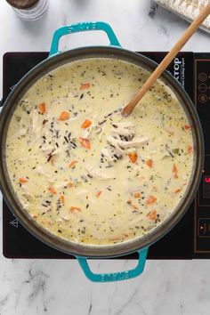 a pot filled with soup sitting on top of a stove next to a wooden spoon