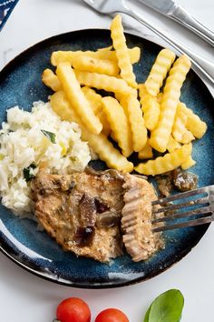 a blue plate topped with meat, rice and french fries next to some cherry tomatoes