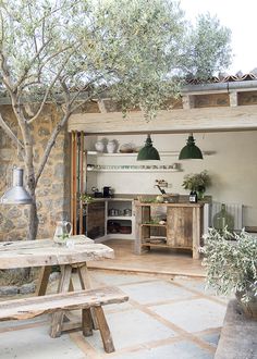 an outdoor kitchen and dining area with table, bench and potted plant in foreground