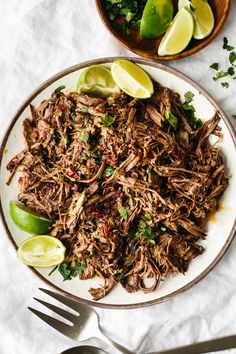 shredded beef with limes and cilantro on a plate next to a bowl of salsa