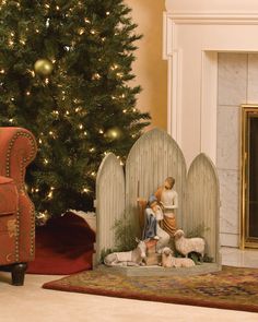 a christmas tree is in the background with two figurines and a fireplace mantel