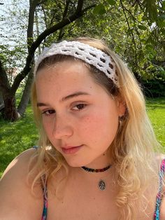 a young woman wearing a headband sitting in the grass