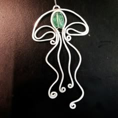 an intricately designed pendant with a green stone in the center on a black background