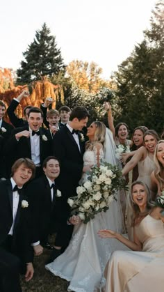 a large group of people in formal wear posing for a photo with their arms around each other