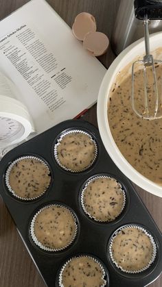 muffin batter in a cupcake tin next to an open book