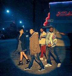 four people standing in the street at night