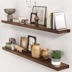 two wooden shelves with books, vases and other decorative items on top of them