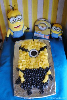 a cake made to look like a despicable minion with grapes and pineapples