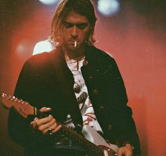 a man with long hair playing an electric guitar in front of microphones and lights