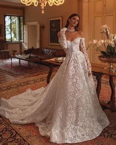 a woman in a white wedding dress standing on a rug next to a chandelier