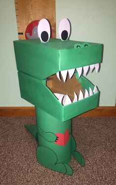 a cardboard alligator with its mouth open on the floor