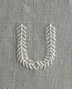 the stitches are stitched together to form an o - shaped letter on a piece of gray fabric