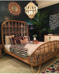 a rattan bed with pillows and blankets on it in a room decorated with plants