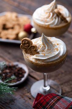 two desserts with whipped cream on top and cookies in the background, sitting on a wooden table