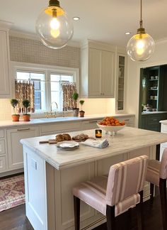 a large kitchen with an island in the middle and two hanging lights over it's sink