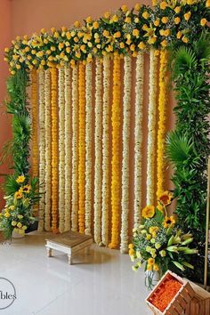 an arrangement of yellow flowers and greenery on the side of a wall in a room