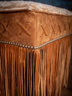 an ottoman with fringes and beads on it