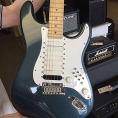 an electric guitar being held up by someone's hand in front of some amps