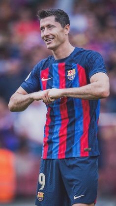 a soccer player is smiling and holding his hand out to the sidelines while standing in front of an audience