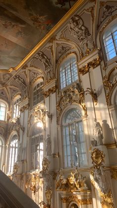 an ornately decorated building with gold trimmings and paintings on the walls, along with large windows