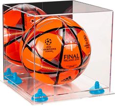 two orange soccer balls in a clear display case with blue plastic pegs on the bottom