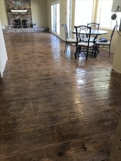 an empty living room with hard wood flooring and chairs in the corner, next to a brick fireplace