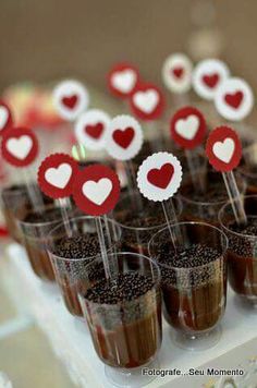 small cups filled with desserts on top of a white tray topped with red and white hearts