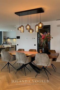 a dining room table and chairs with lights hanging from the ceiling