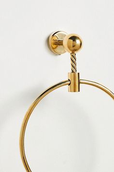 a pair of gold colored metal hoops on a white wall with a ball hanging from the end