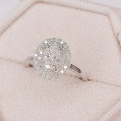 a diamond ring sitting on top of a white velvet cushion in a box with its lid open