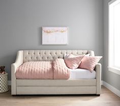 a white daybed with pink pillows in a gray and white bedroom area next to a painting on the wall