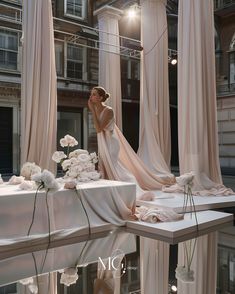 a woman in a wedding dress standing next to a table with white flowers on it