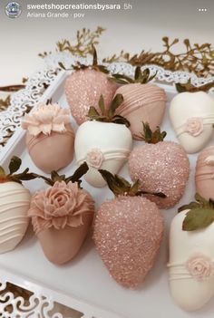 chocolate covered strawberries are arranged on a white platter with pink flowers and leaves