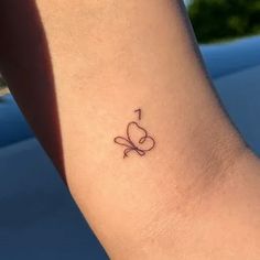 a small tattoo on the ankle of a woman's foot, with an arrow in the shape of a heart