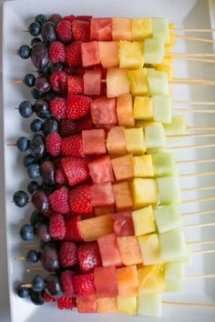 fruit skewers are arranged on a white plate