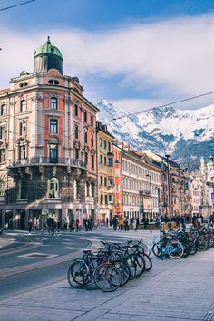 many bicycles are parked on the side of the road in front of buildings with mountains in the background