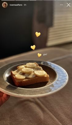 a person holding a plate with slices of banana on it and hearts floating above the plate