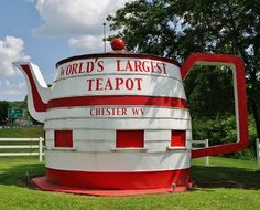 a large teapot shaped sign in the middle of a field