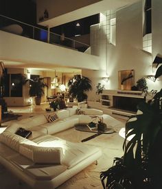 a living room filled with white furniture and lots of plants on top of the floor