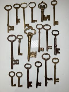 an assortment of antique keys arranged on a white surface