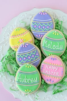 decorated cookies on a plate with the words happy easter written on them in bright colors