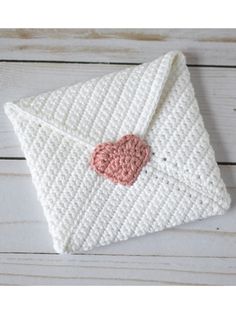 a crocheted envelope with a pink heart on the front and white envelope in the back