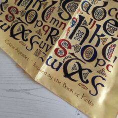 two books with gold covers and black lettering on them, sitting on a white table