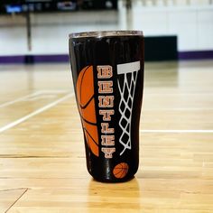 a black tumbler cup sitting on top of a basketball court