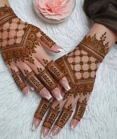 two hands with henna designs on them and a rose in the background, one is pink