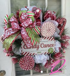 the wreath is decorated with candy canes and ribbons on it's front door