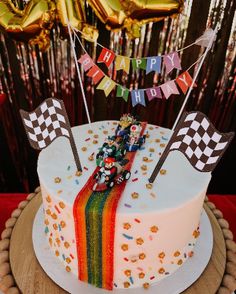 a birthday cake is decorated with flags and streamers for a race car themed party