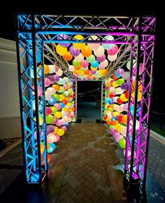 an archway decorated with colorful balloons in the dark