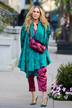 a woman is walking down the street with her hand in her pocket and wearing pink pants